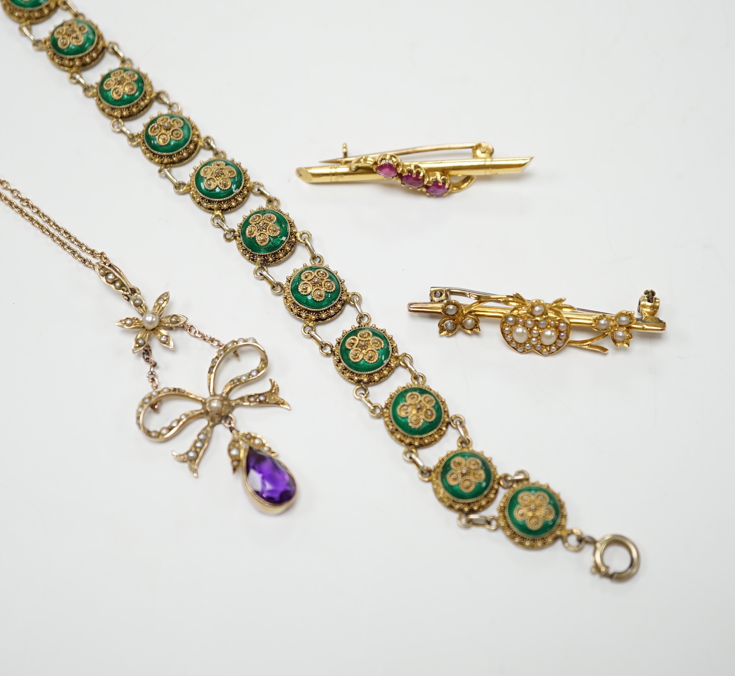 An Edwardian yellow metal, amethyst and split pearl set drop pendant, 52mm, on a yellow metal fine link chain, 45cm, a similar yellow metal and seed pearl set twin hearts bar brooch, a yellow metal and three stone ruby s